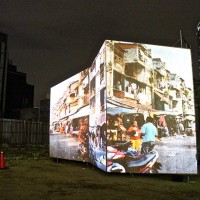 岩井優「ホワイトビル・ウォッシング」。ビルが立ち並ぶ六本木の一角に、カンボジアのスラム街をプロジェクターで投影して見せた作品